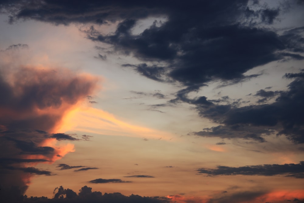 a plane flying through a cloudy sky at sunset