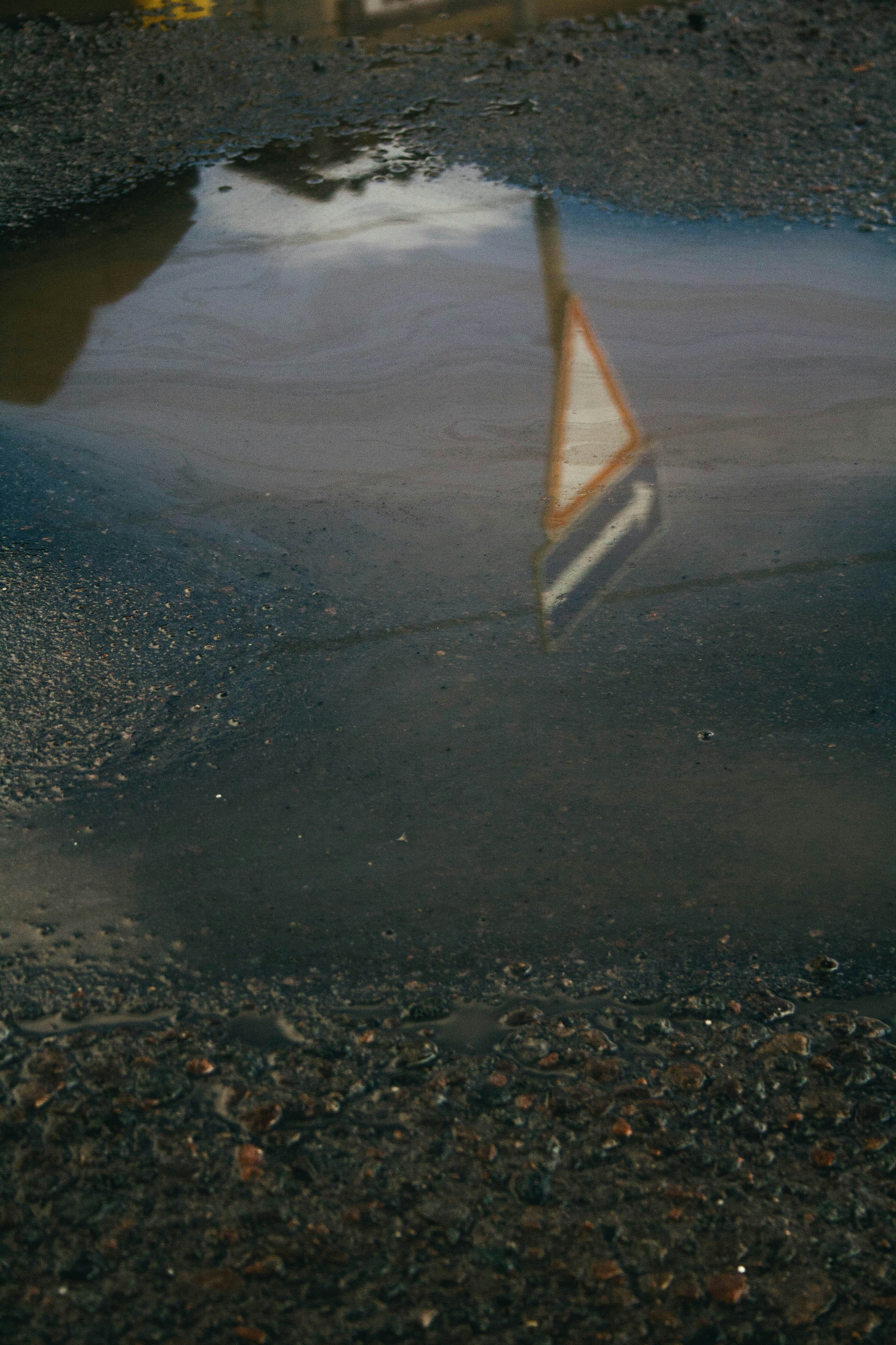 a reflection of a traffic sign in a puddle of water