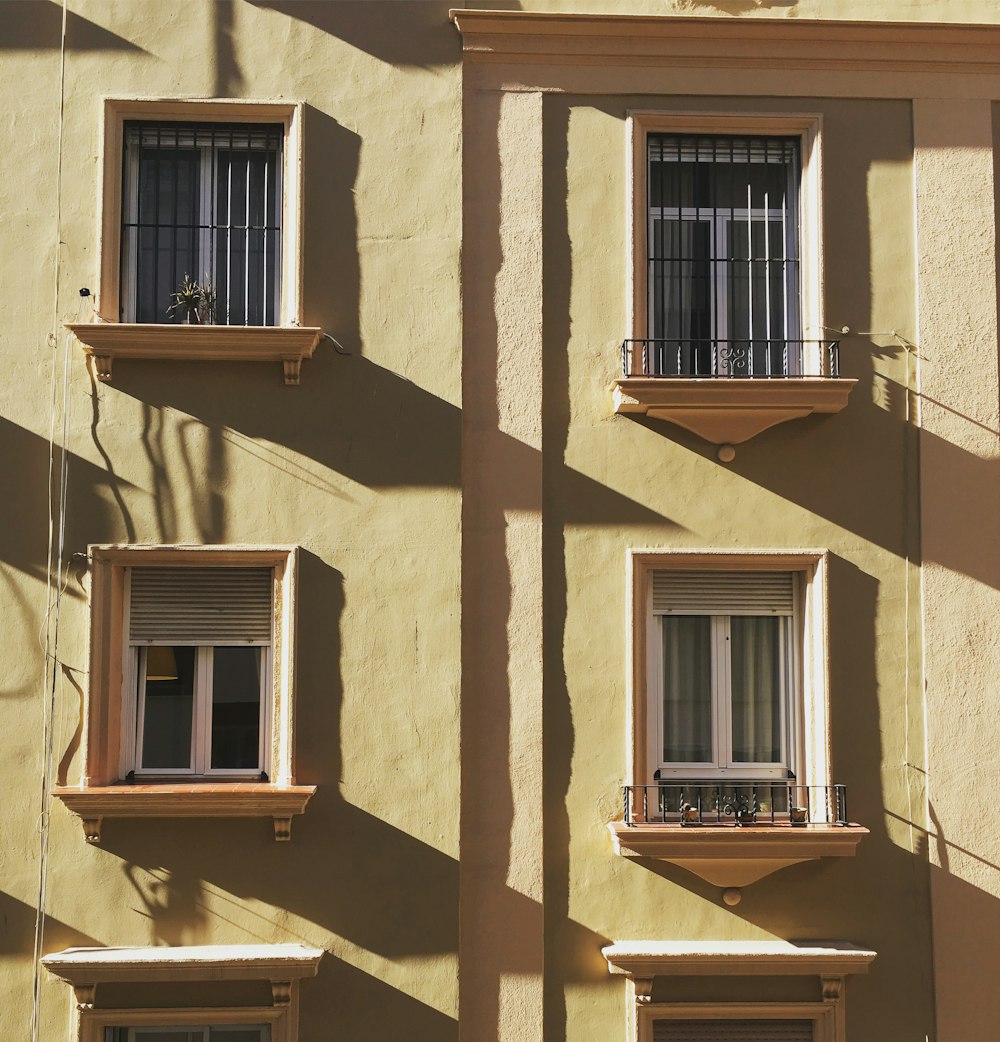 a yellow building with three windows and two balconies