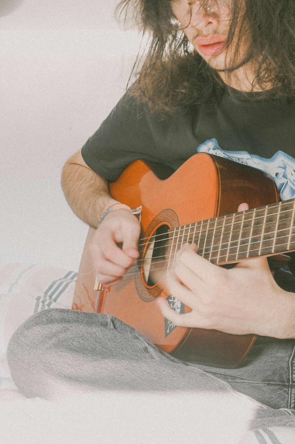 a man sitting on a bed playing a guitar