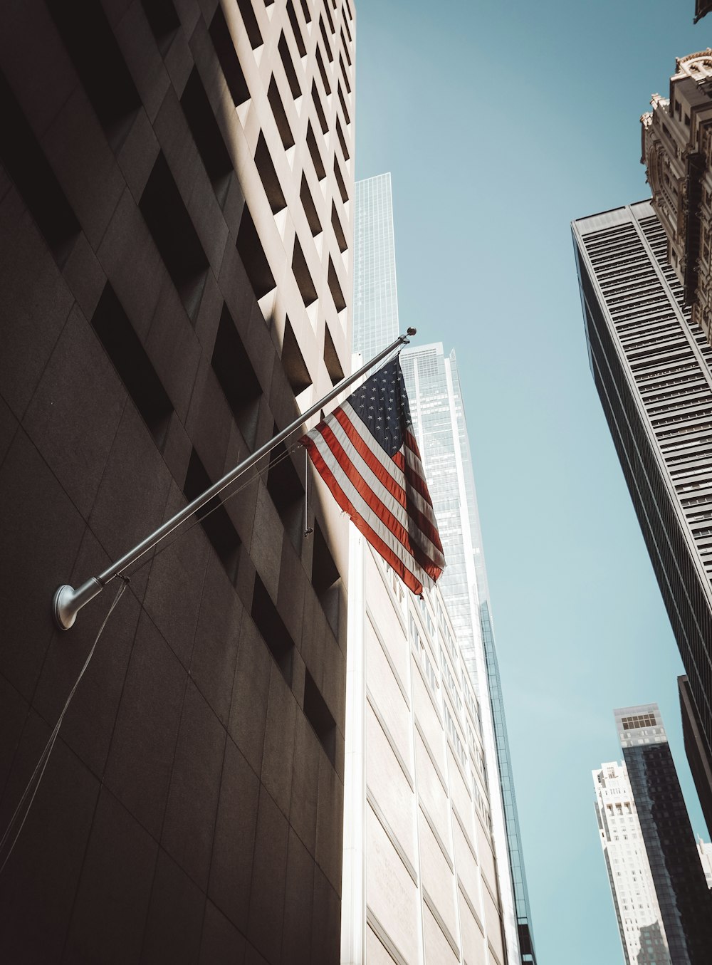 an american flag hanging from the side of a tall building