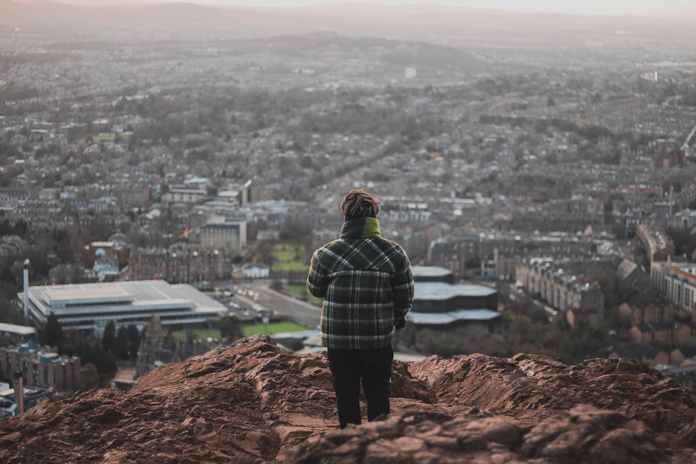 a man standing on top of a mountain looking at a city