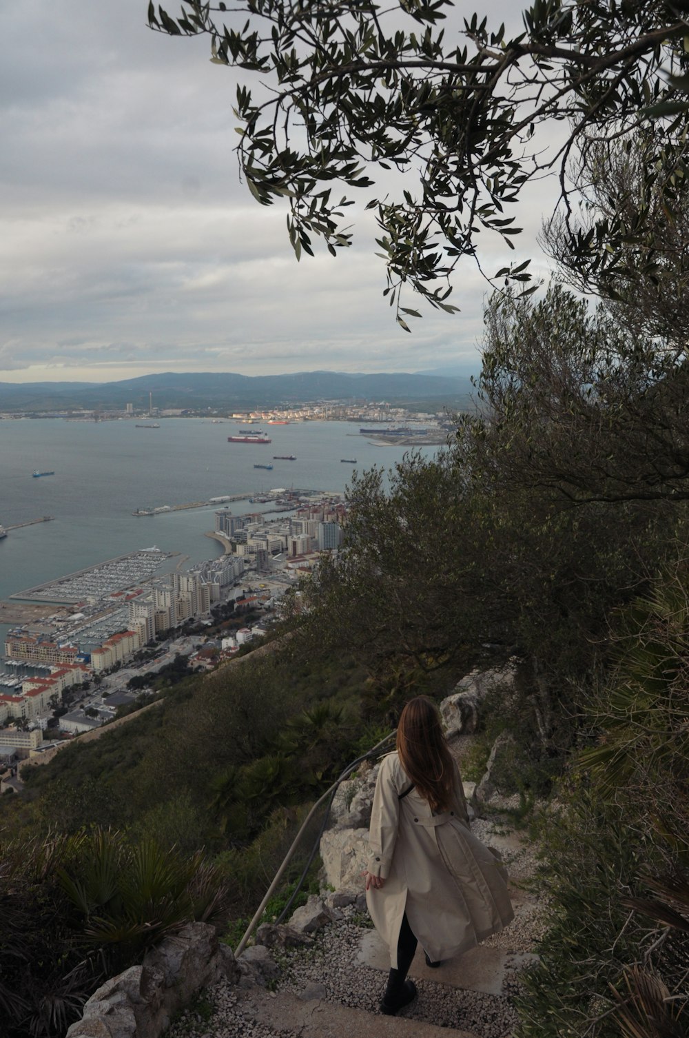 a woman walking up a hill with a view of a city