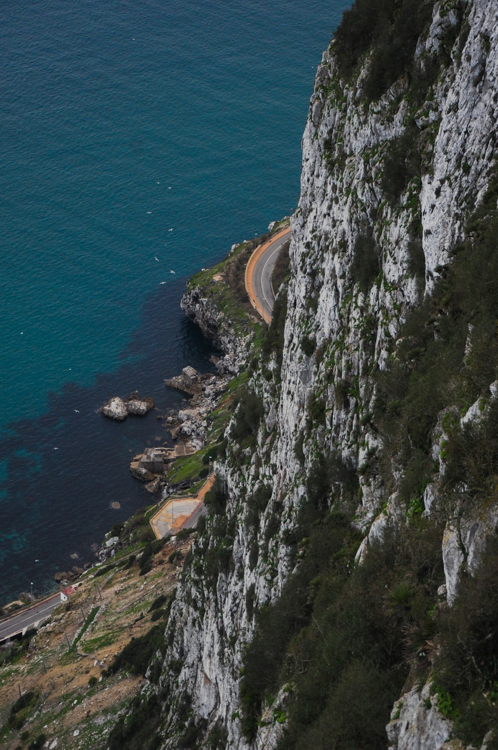 a road on the side of a mountain next to a body of water