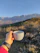 A happy customer holding a cup of coffee with a scenic mountain backdrop.