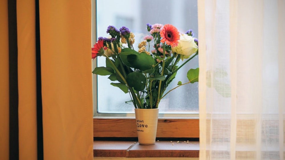 a vase of flowers sitting on a window sill