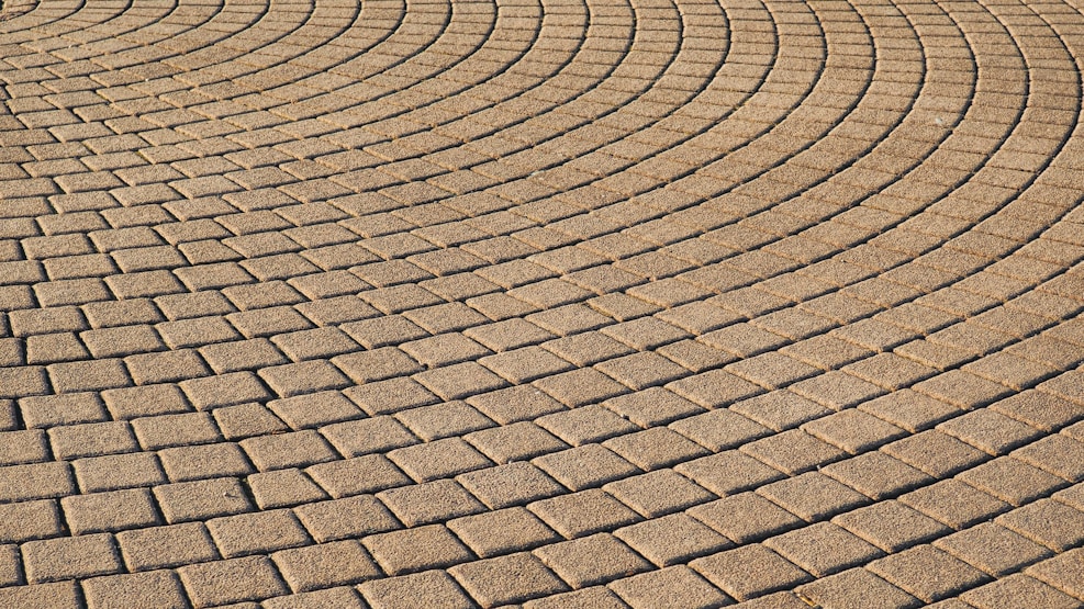 Interlocking brick pavement forms an intricate pattern of curved lines. The bricks are uniformly arranged, creating a textured and visually captivating surface.