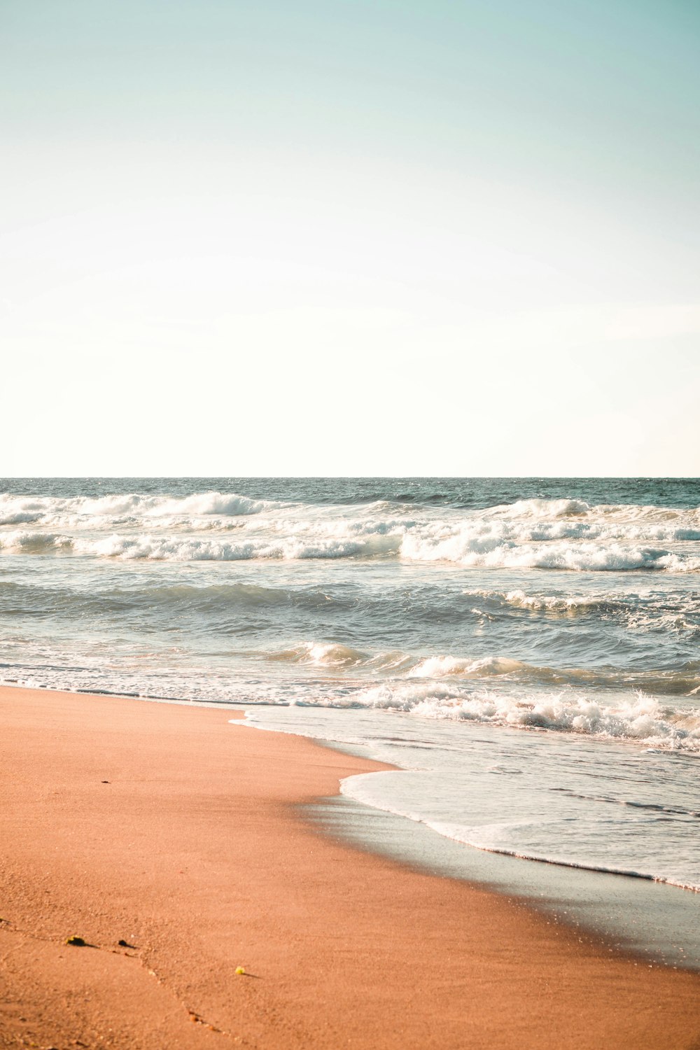 a person walking on the beach with a surfboard