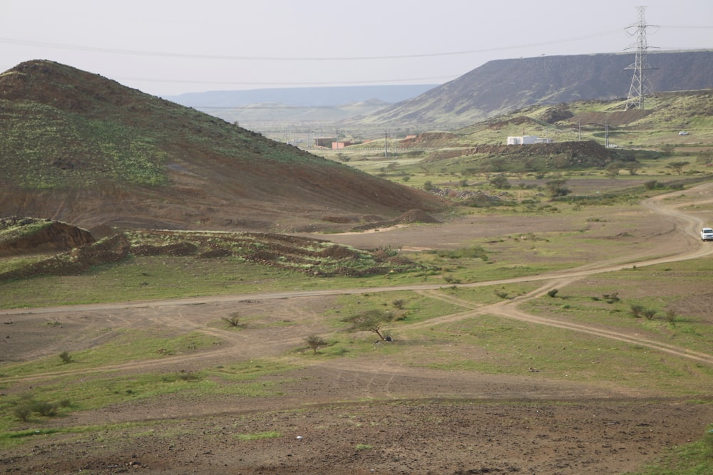 a truck driving down a dirt road near a hill