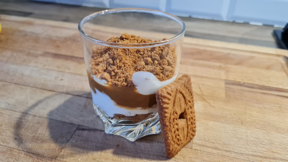 a glass of ice cream and cookies on a wooden table
