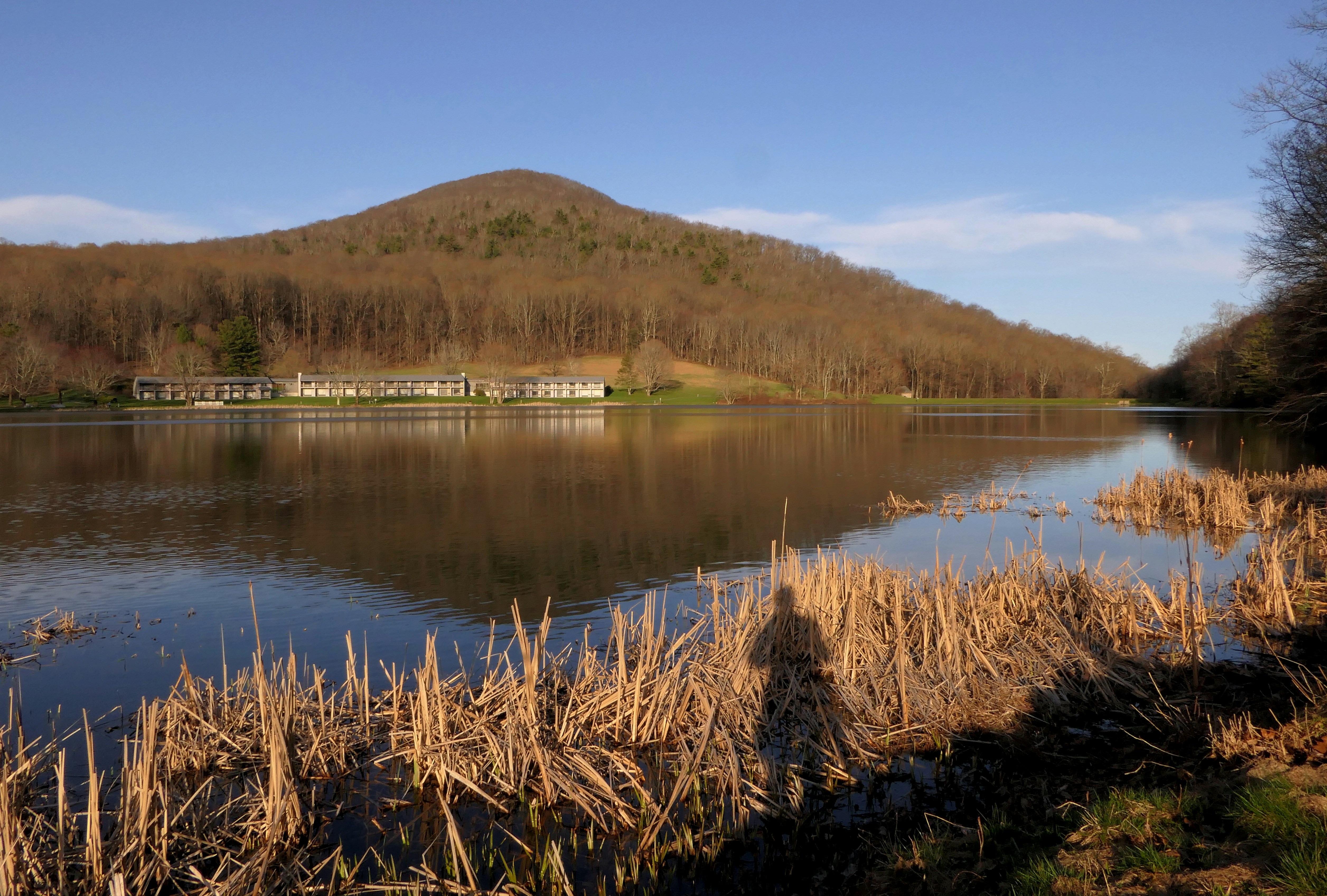 a body of water surrounded by a lush green hillside, trails near this Blue Ridge Mountain lodge are a favorite hiking spot