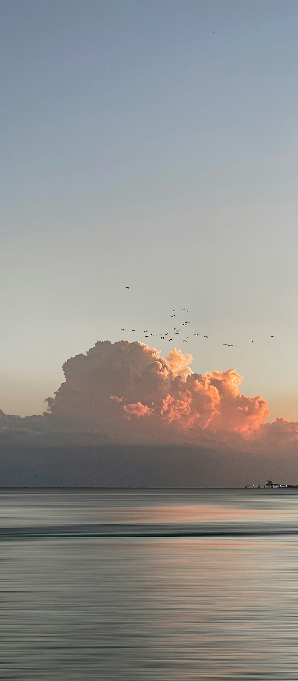 a large cloud in the sky over a body of water