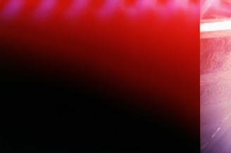 An abstract image dominated by bright red and black colors, possibly due to light leaks or intentional photographic effects.