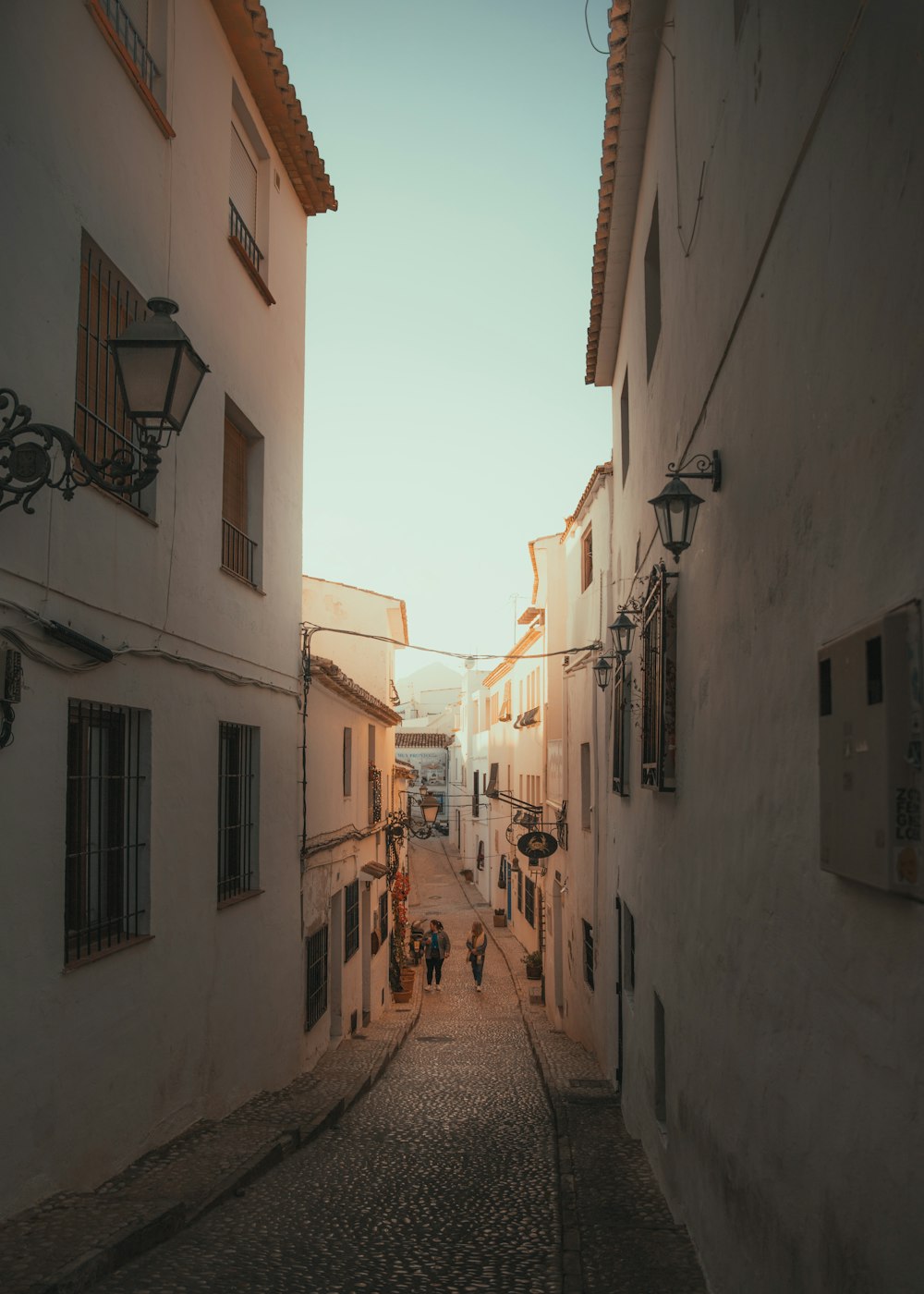 a narrow street with people walking down it