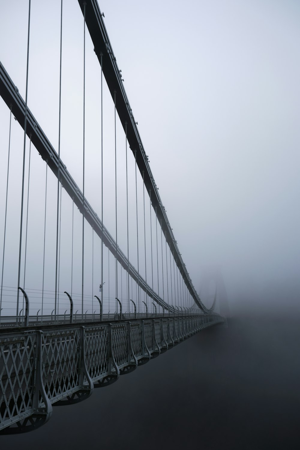 a long suspension bridge with fog in the background