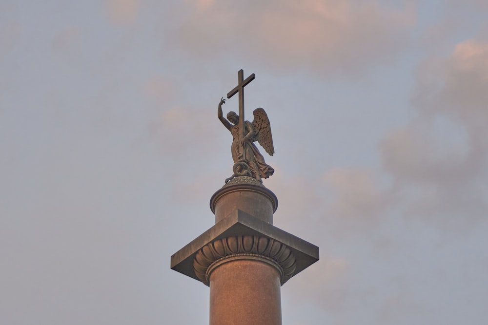 a statue of an angel holding a cross on top of a building