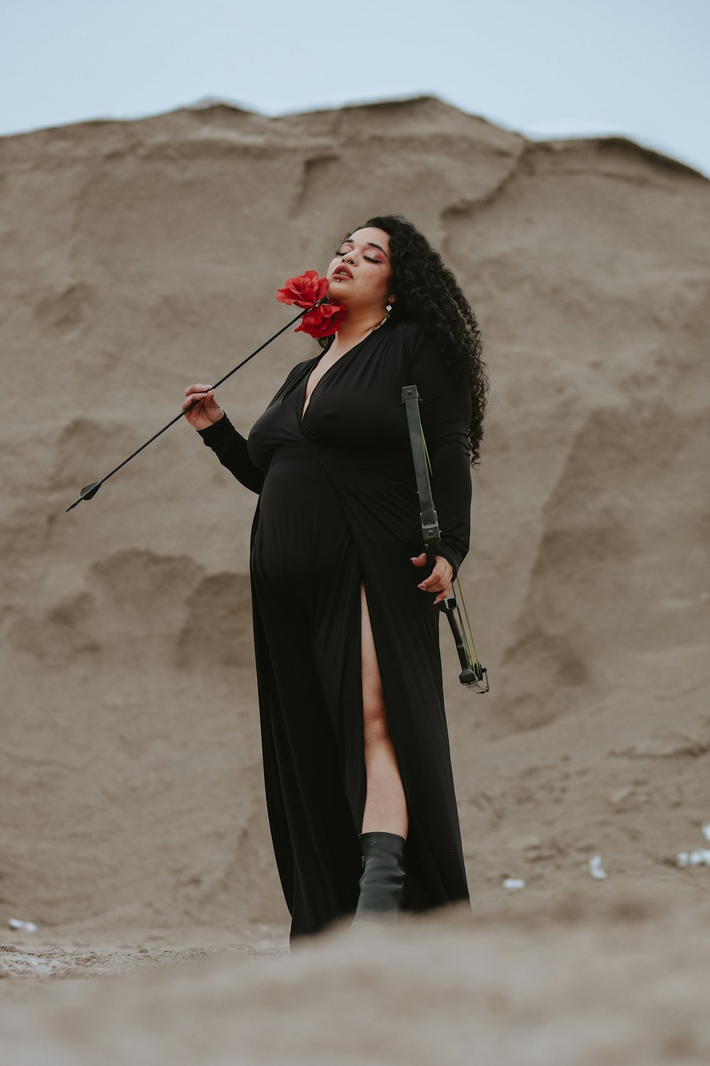 a woman in a long black dress holding a flower