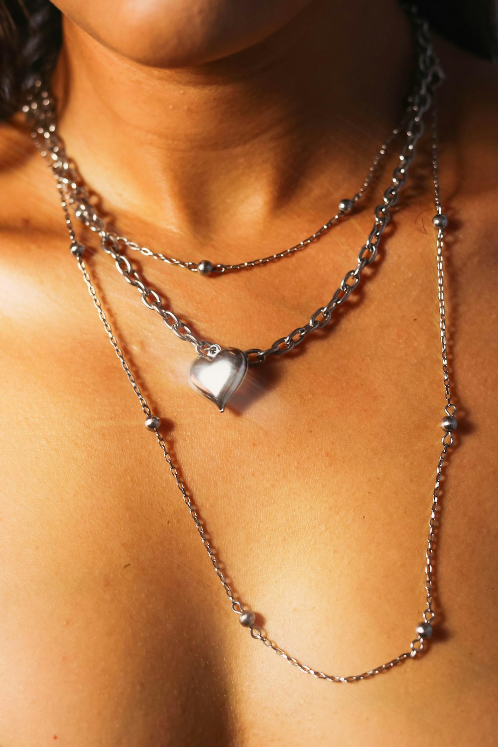 a woman wearing a necklace with a heart on it