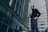 Photo of a confident man standing in front of modern office buildings.