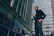 Photo of a confident security guard standing in front of a modern office building at dusk.