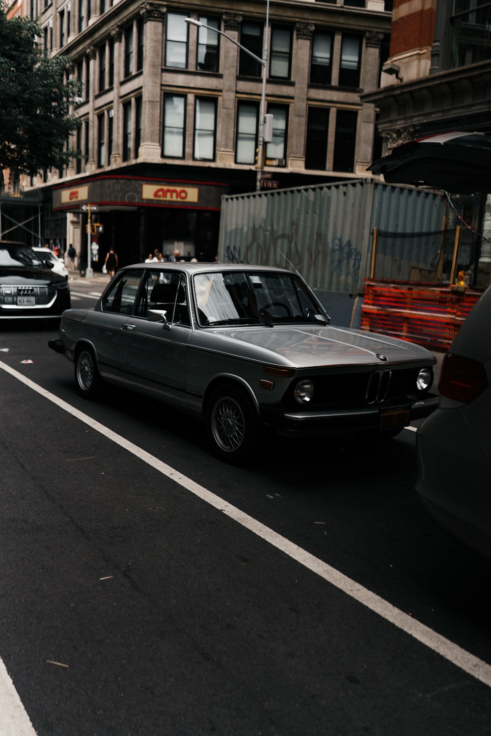 a black car driving down a street next to tall buildings