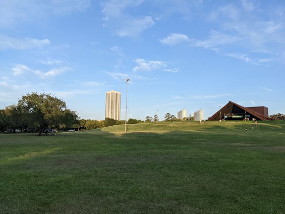A bright, airy pavilion in a lush University City park with people enjoying a sunny day.