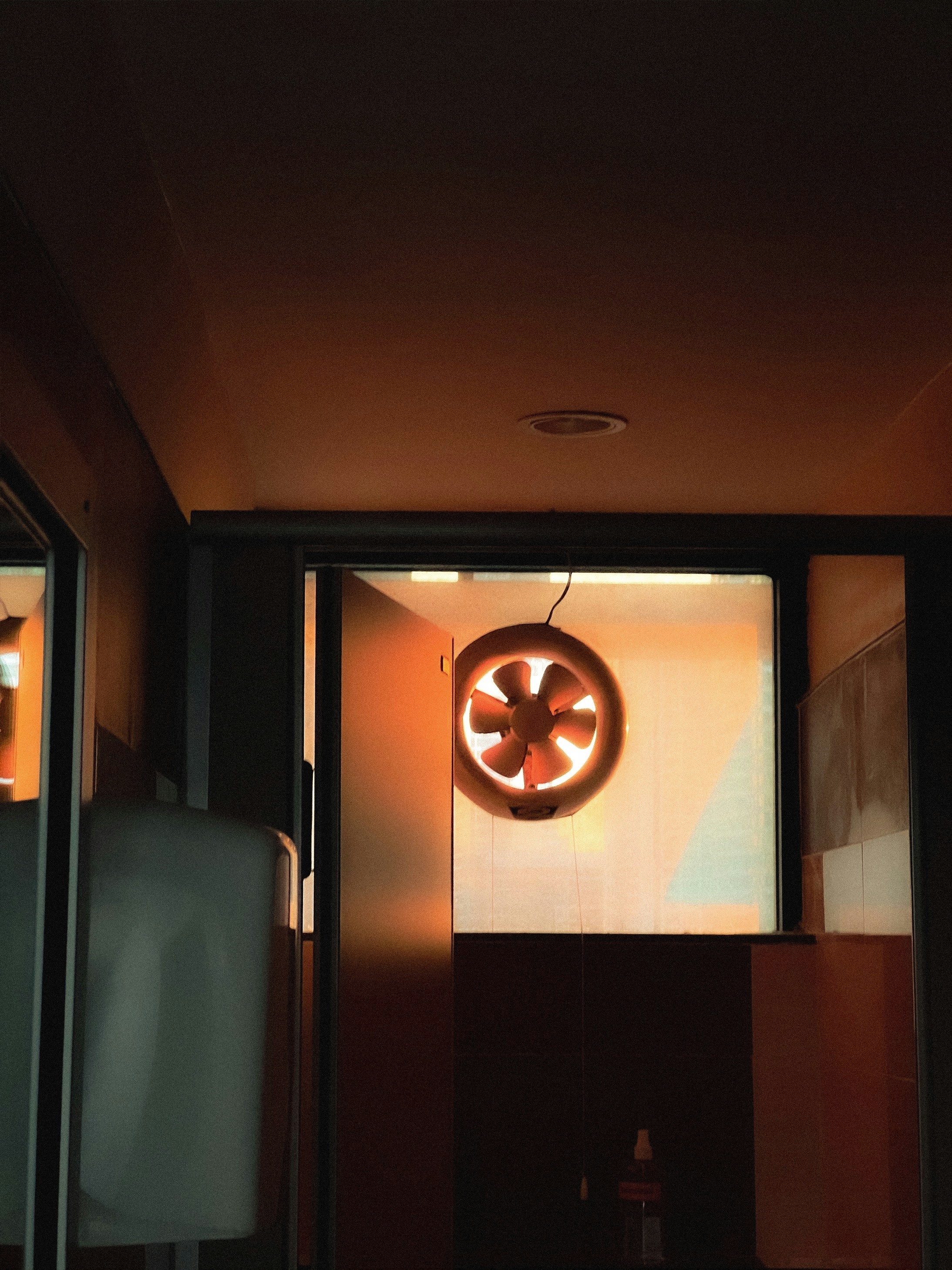 Round exhaust fan mounted on white bathroom wall