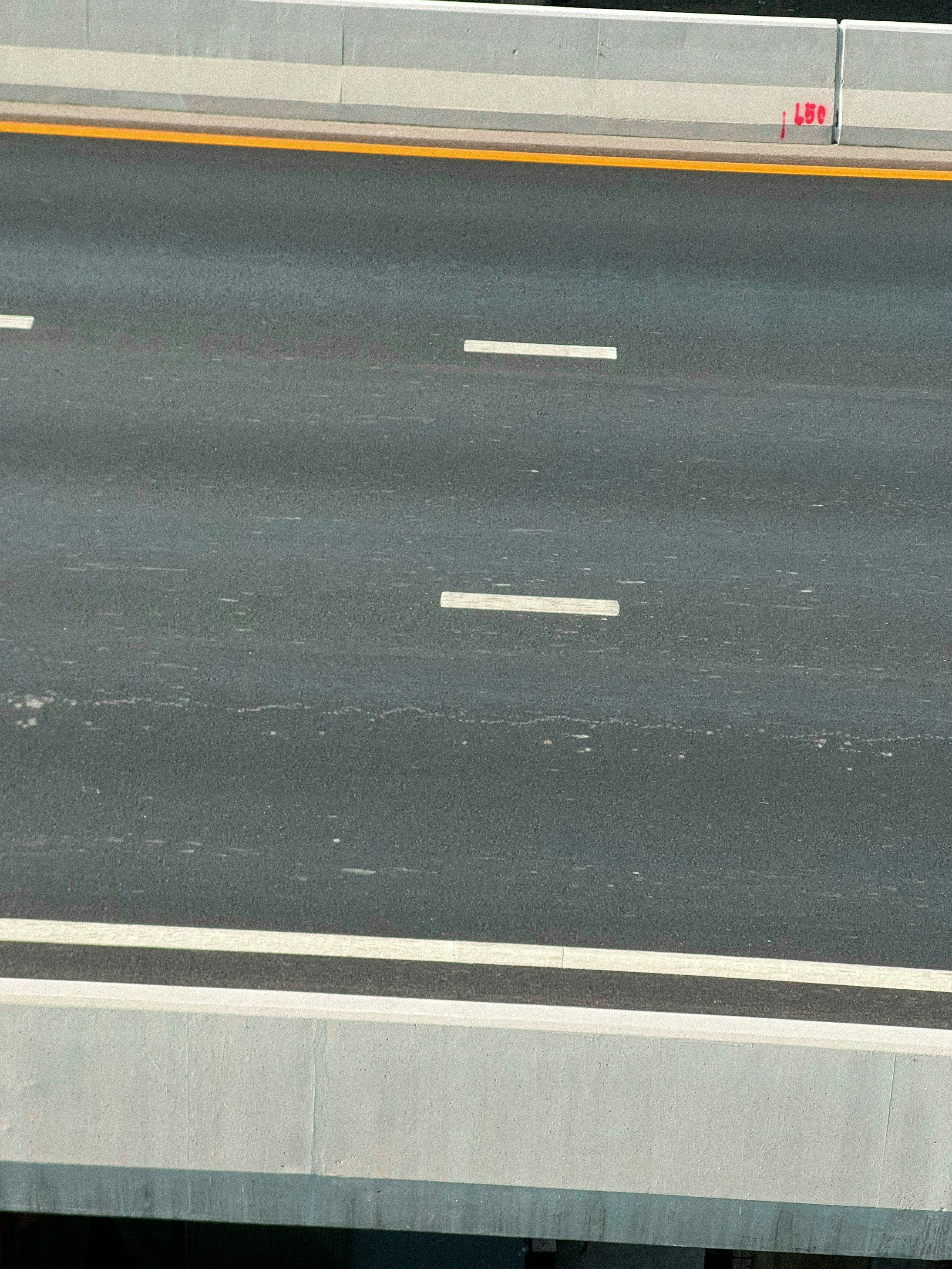 Concrete road divider barriers on busy highway, bright daylight, well-lit road infrastructure