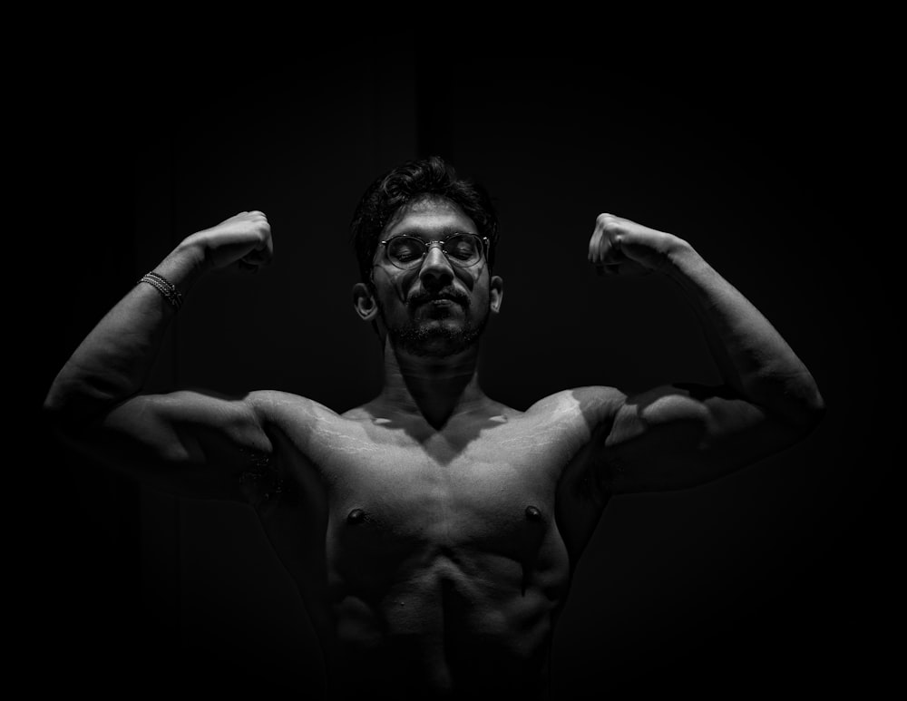a man flexing his muscles in the dark