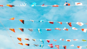 A vibrant collage of international flags fluttering against a clear blue sky