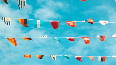 Flags of many nations waving together under a hopeful sky.