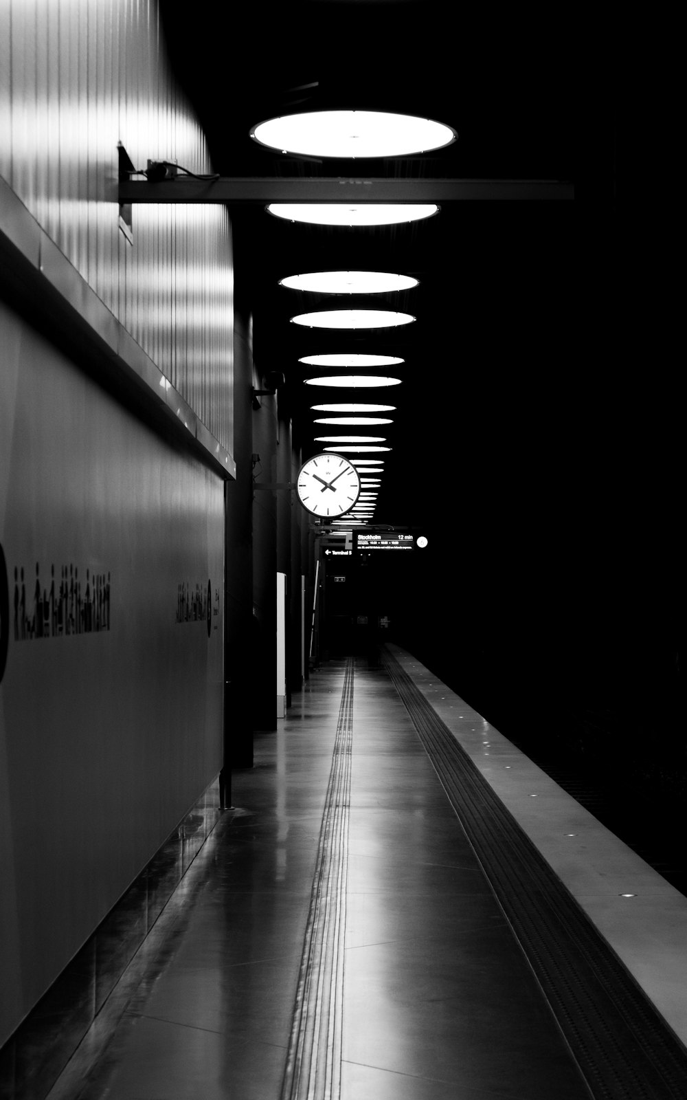 a black and white photo of a long hallway with a clock