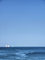 A vibrant blue ocean with a cargo ship sailing in the distance.