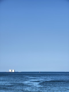 A vibrant blue ocean with a cargo ship sailing in the distance.