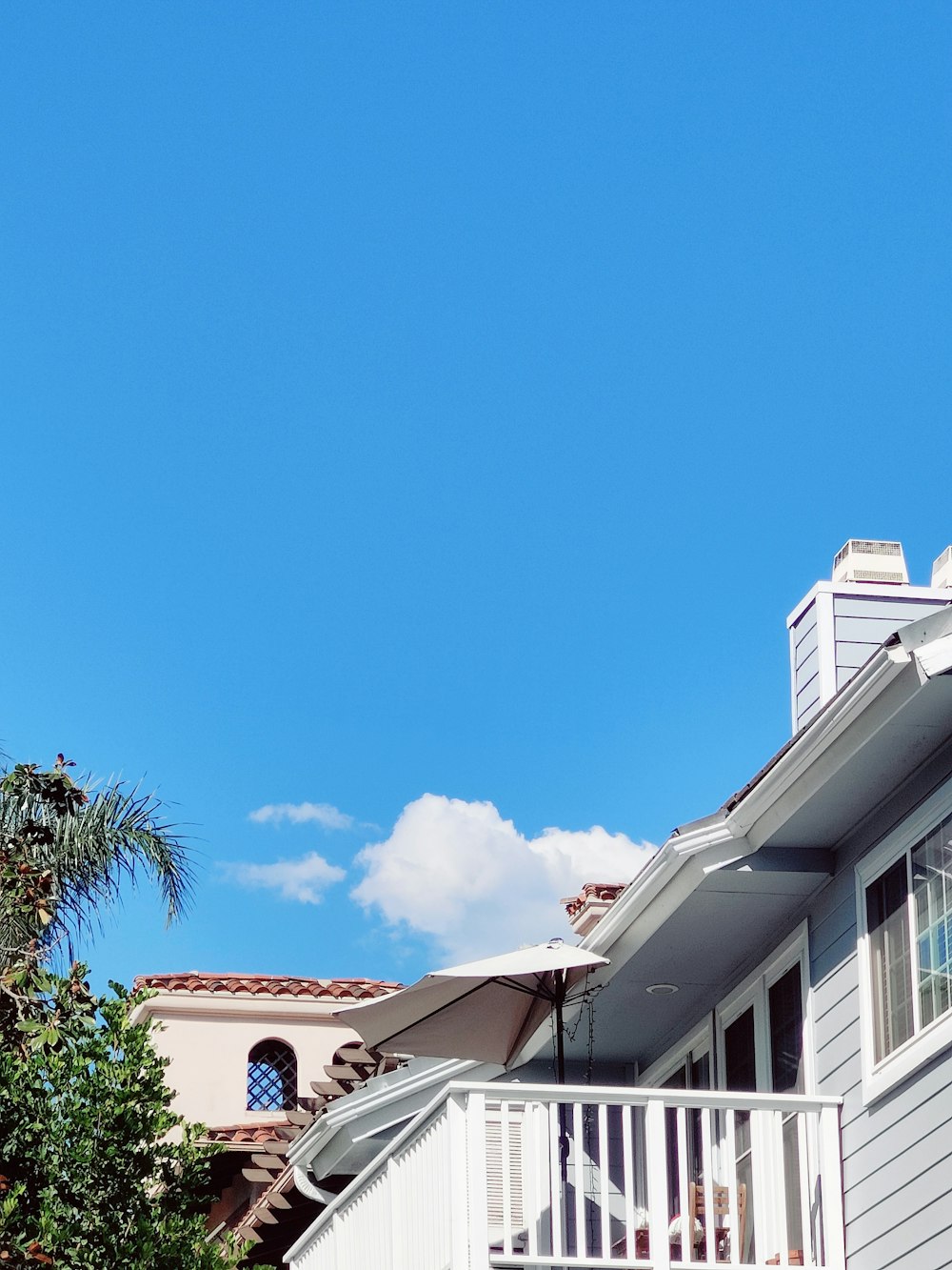 a white house with a balcony and a palm tree