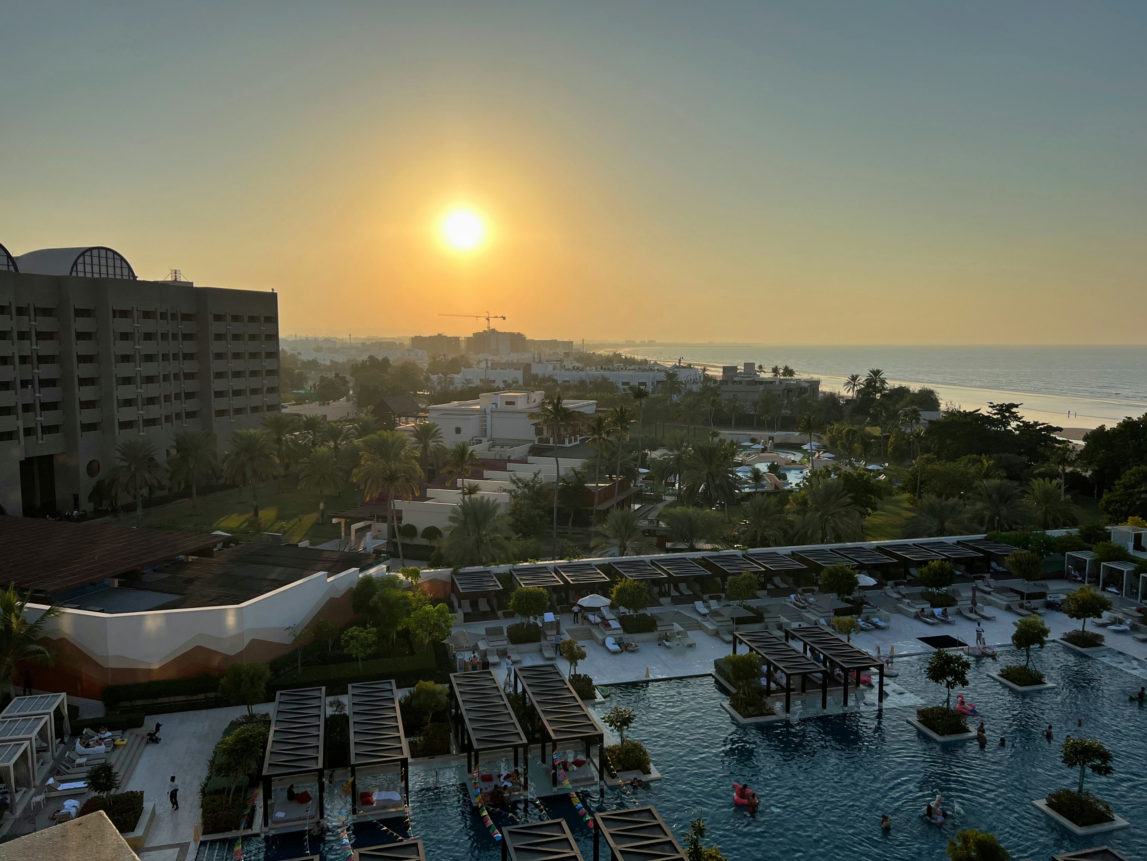the sun is setting over a large swimming pool