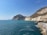 A scenic view of a turquoise coastline with a car parked on a cliffside overlooking the sea.