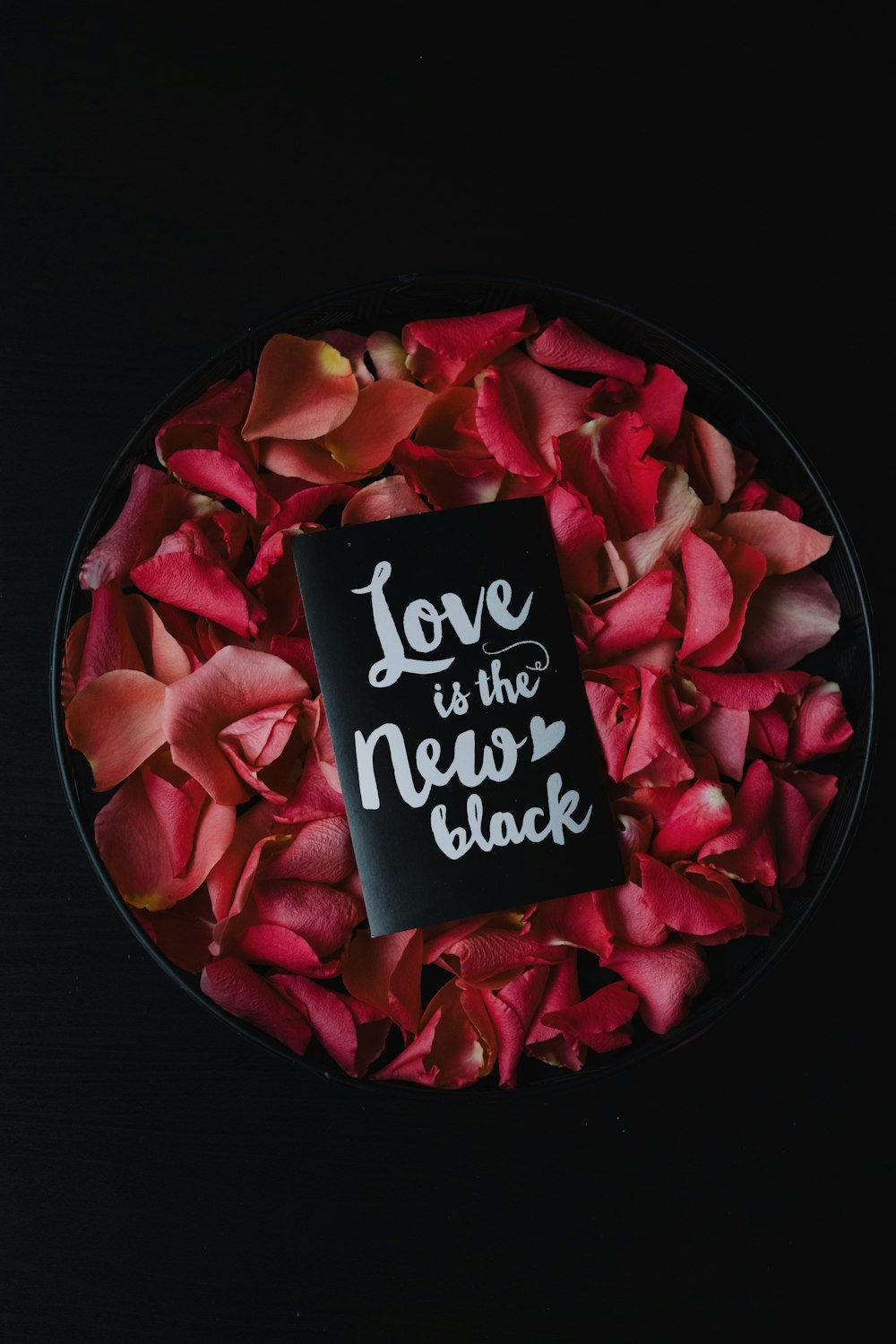 a plate of rose petals with a card saying love is the new black