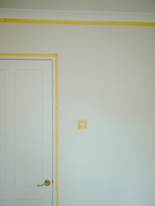 a room with a white door and a yellow strip on the wall