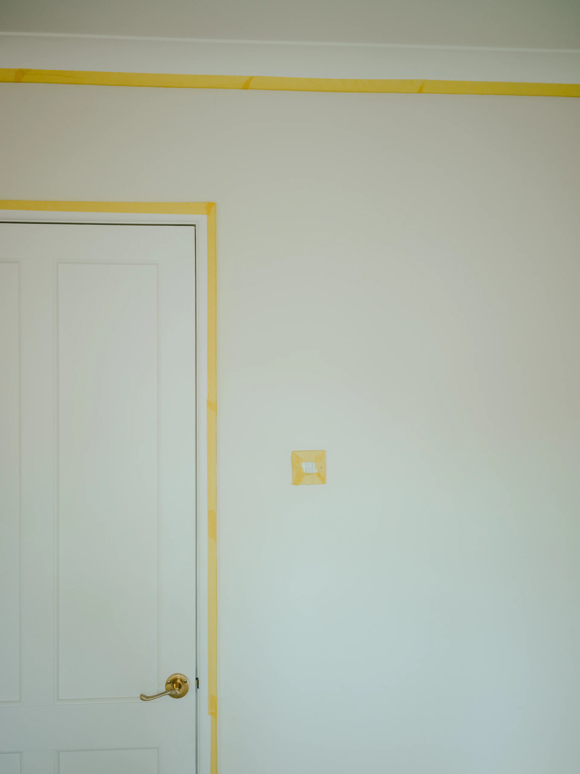 a room with a white door and a yellow strip on the wall