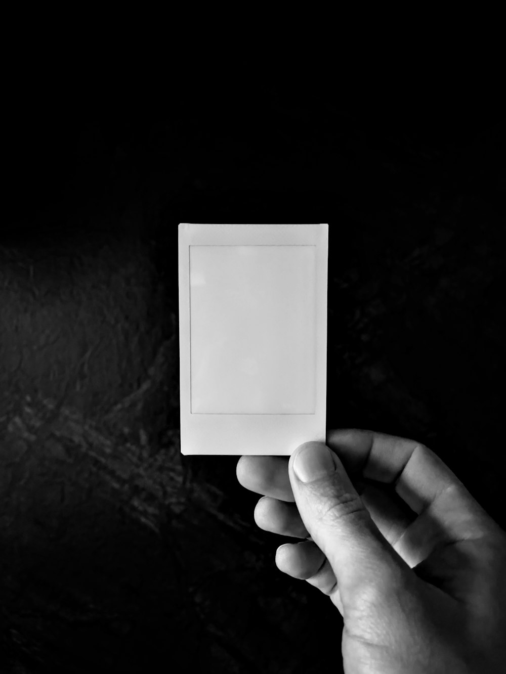 a black and white photo of a hand holding a square object