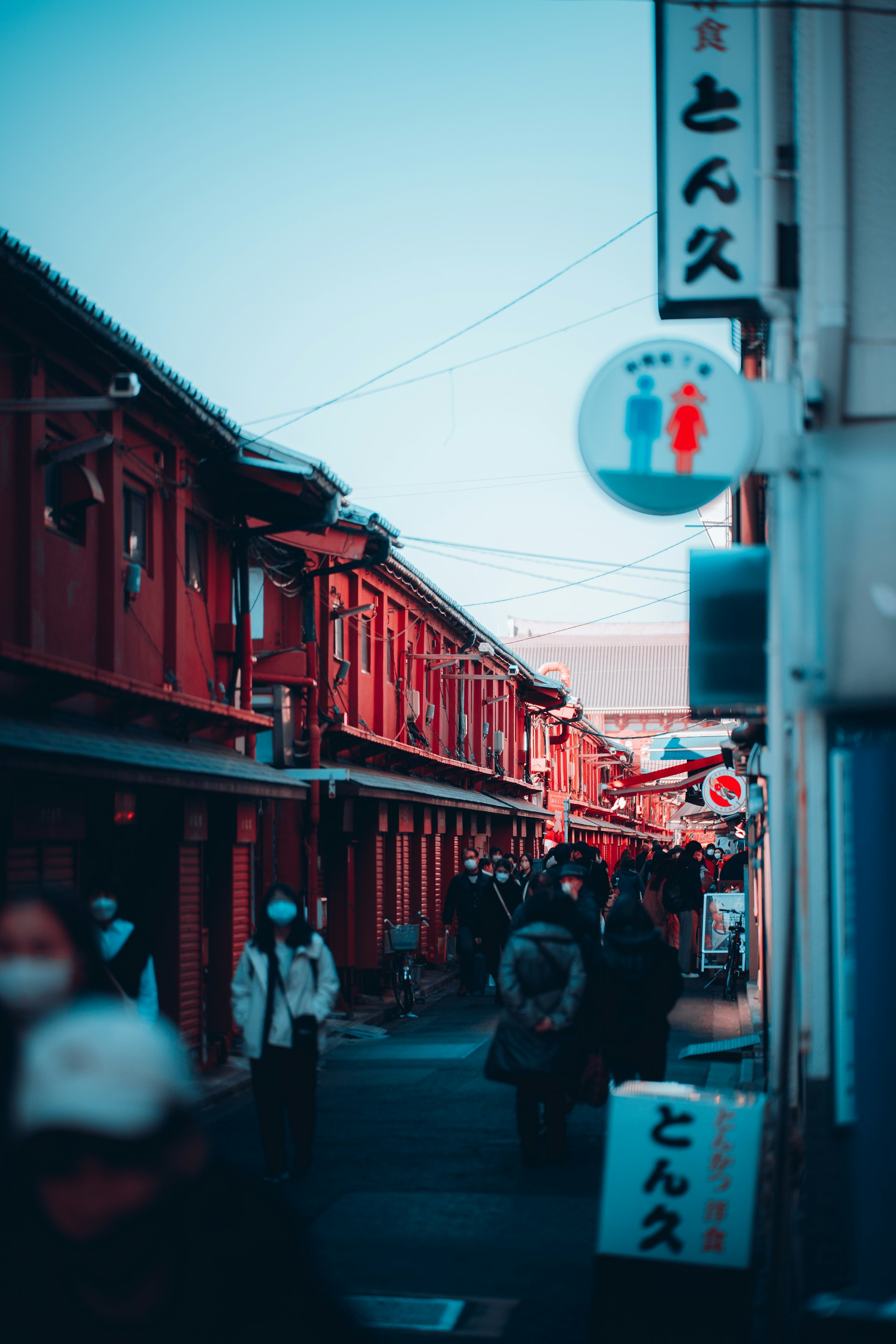 a group of people walking down a street next to red buildings