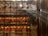 Intricately decorated interior of a traditional temple with numerous hanging spiral incense coils and red prayer tags. Sunlight filters through the space, creating a serene atmosphere. Ornate metalwork and glowing lanterns add to the ambiance.