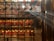 Intricately decorated interior of a traditional temple with numerous hanging spiral incense coils and red prayer tags. Sunlight filters through the space, creating a serene atmosphere. Ornate metalwork and glowing lanterns add to the ambiance.