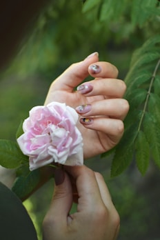 a woman holding a pink flower in her hands