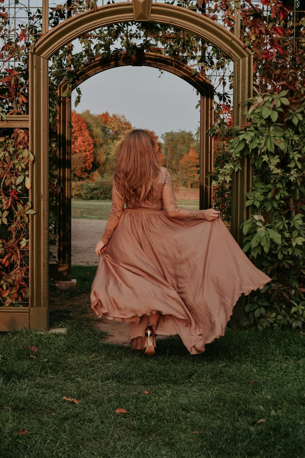 a woman in a long dress walking through a garden