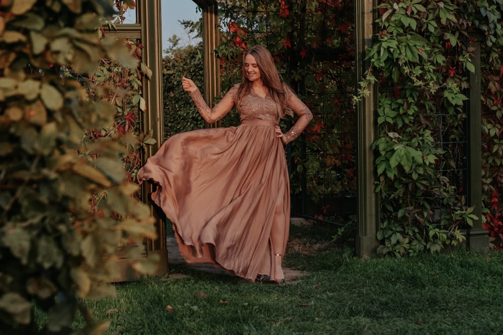 a woman in a long dress standing in a garden