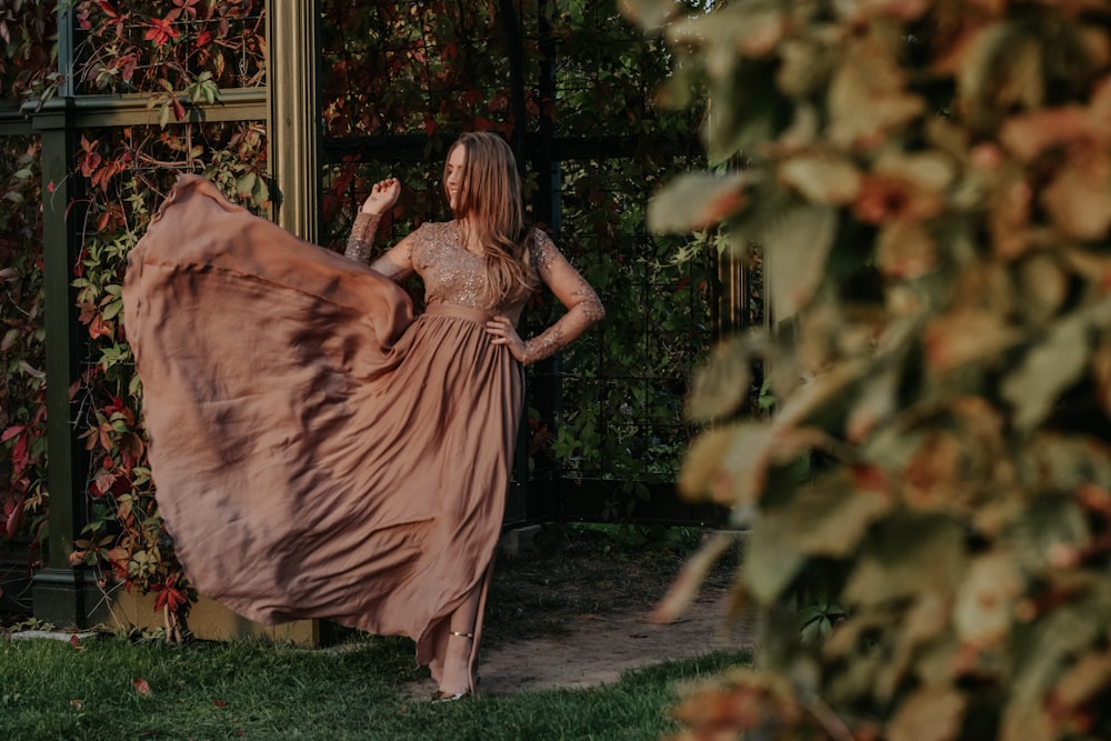 a woman in a long dress standing in a garden