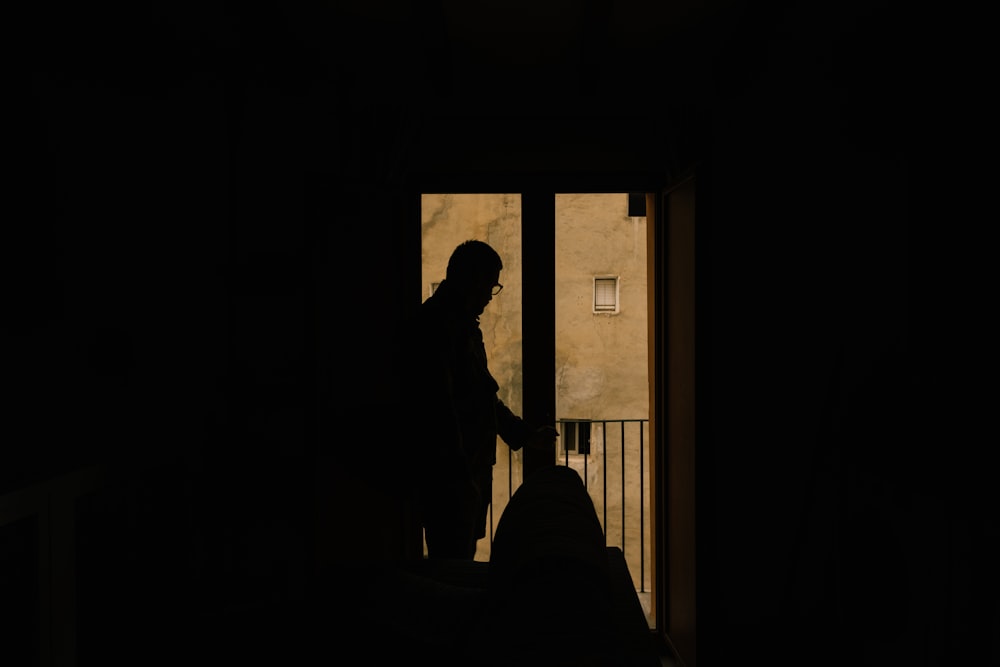 a silhouette of a person standing in front of a door