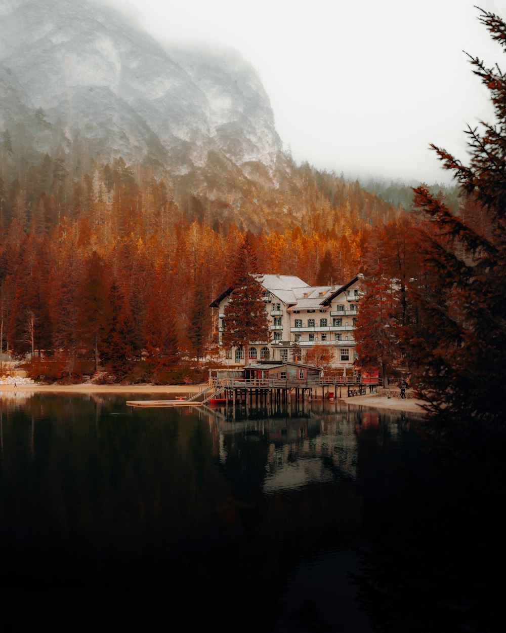 a house on the shore of a lake with a mountain in the background